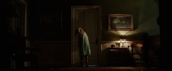 Movie still from “Annabelle: Creation” (2017), directed by David F. Sandberg – A woman standing in front of an open door in a dark room; Wide shot, Low angle