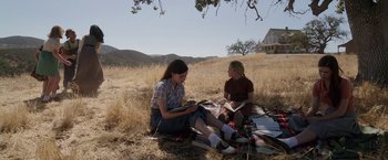Movie still from “Annabelle: Creation” (2017), directed by David F. Sandberg – Two women sitting on a blanket in a field; Wide shot, High angle