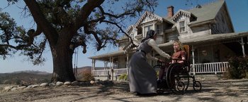 Movie still from “Annabelle: Creation” (2017), directed by David F. Sandberg – A woman in an old fashioned dress pushing an old fashioned wheelchair; Wide shot, Low angle