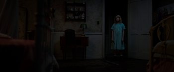 Movie still from “Annabelle: Creation” (2017), directed by David F. Sandberg – A woman standing in a dark room holding a knife; Wide shot, Over the shoulder angle