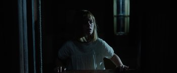 Movie still from “Annabelle: Creation” (2017), directed by David F. Sandberg – A girl in a white shirt is standing in a dark room; Medium shot, Low angle