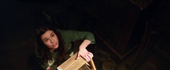 Movie still from “Annabelle: Creation” (2017), directed by David F. Sandberg – A woman in a green shirt holding a wooden board; Medium shot, Overhead angle