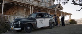Movie still from “Annabelle: Creation” (2017), directed by David F. Sandberg – An old police car parked on the side of the road; Wide shot, Low angle