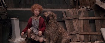Movie still from “Annie” (1982), directed by John Huston – A little girl sitting next to a brown dog; Medium shot, High angle