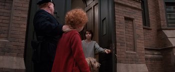 Movie still from “Annie” (1982), directed by John Huston – A boy and a dog standing in front of a door; Medium shot, Over the shoulder angle