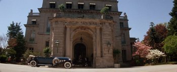 Movie still from “Annie” (1982), directed by John Huston – An antique car parked in front of a building; Extreme Wide shot, Low angle
