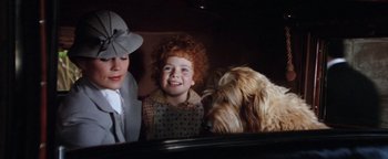 Movie still from “Annie” (1982), directed by John Huston – A woman and a child with a dog in a car; Close Up shot, Over the shoulder angle