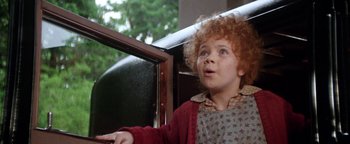 Movie still from “Annie” (1982), directed by John Huston – A young child sitting in a car looking out the window; Close Up shot, High angle