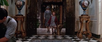 Movie still from “Annie” (1982), directed by John Huston – A woman and a child walking down a hall way with a dog; Wide shot, Low angle