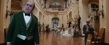 Movie still from “Annie” (1982), directed by John Huston – A group of people standing in a large room; Wide shot, Low angle