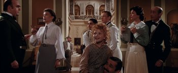 Movie still from “Annie” (1982), directed by John Huston – A group of people standing in a room; Medium shot, Over the shoulder angle