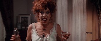 Movie still from “Annie” (1982), directed by John Huston – A woman with red curly hair holding a wine glass; Close Up shot, Low angle