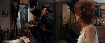 Movie still from “Annie” (1982), directed by John Huston – A man and a woman standing next to each other in a room; Medium shot, Over the shoulder angle