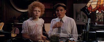 Movie still from “Annie” (1982), directed by John Huston – A woman and a girl standing next to each other in a room; Medium shot, High angle