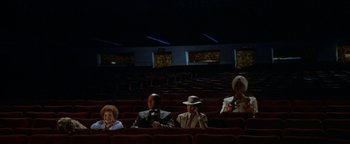 Movie still from “Annie” (1982), directed by John Huston – A group of people sitting in a movie theater; Wide shot, High angle