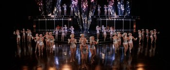 Movie still from “Annie” (1982), directed by John Huston – A group of women are performing on a stage; Extreme Wide shot, High angle