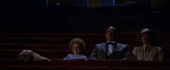 Movie still from “Annie” (1982), directed by John Huston – A man and a child sitting in a theater; Wide shot, High angle