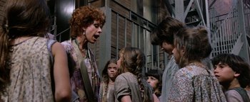 Movie still from “Annie” (1982), directed by John Huston – A group of people standing next to each other on a street; Medium shot, Over the shoulder angle
