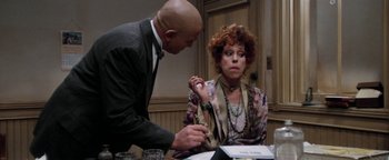 Movie still from “Annie” (1982), directed by John Huston – A man and a woman sitting at a table; Medium shot, Over the shoulder angle