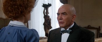 Movie still from “Annie” (1982), directed by John Huston – A man in a suit and bow tie talking to a woman; Close Up shot, Over the shoulder angle