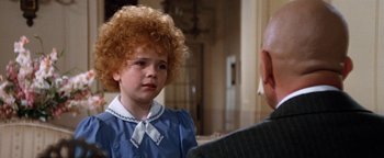 Movie still from “Annie” (1982), directed by John Huston – A young girl with a curly red hair and a white shirt is talking to an older man; Close Up shot, Over the shoulder angle