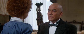 Movie still from “Annie” (1982), directed by John Huston – A man in a suit and bow tie talking to a woman; Close Up shot, Over the shoulder angle