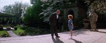Movie still from “Annie” (1982), directed by John Huston – An older man and a young girl standing on a sidewalk; Wide shot, Low angle