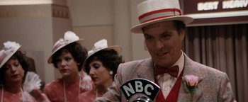 Movie still from “Annie” (1982), directed by John Huston – A group of people dressed up in hats and suits; Close Up shot, Over the shoulder angle