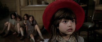 Movie still from “Annie” (1982), directed by John Huston – A little girl wearing a red hat looking at the camera; Close Up shot, High angle