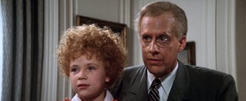 Movie still from “Annie” (1982), directed by John Huston – A man and a boy are standing next to each other; Close Up shot, Over the shoulder angle