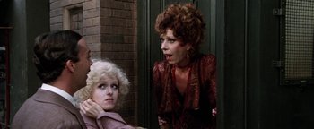 Movie still from “Annie” (1982), directed by John Huston – Two women are standing next to each other in front of a brick wall; Close Up shot, Over the shoulder angle