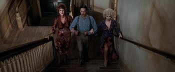 Movie still from “Annie” (1982), directed by John Huston – A man and two women walking down a staircase; Wide shot, High angle