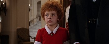 Movie still from “Annie” (1982), directed by John Huston – A young boy with red curly hair wearing a red shirt; Close Up shot, High angle