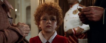 Movie still from “Annie” (1982), directed by John Huston – A young boy in a red shirt and white shirt looking up; Close Up shot, High angle