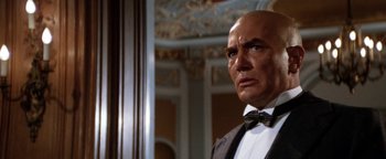 Movie still from “Annie” (1982), directed by John Huston – A bald man in a suit and bow tie looking into a mirror; Close Up shot, Low angle