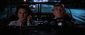 Movie still from “Annie” (1982), directed by John Huston – A man and a woman sitting in a car talking on the phone; Medium shot, Low angle