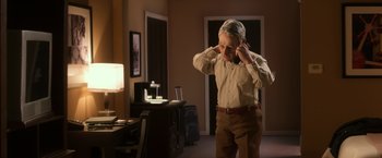 Movie still from “Anomalisa” (2015), directed by Duke Johnson – A man standing in a room with his hands behind his head; Medium shot, Over the shoulder angle