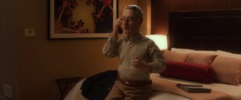 Movie still from “Anomalisa” (2015), directed by Duke Johnson – A man sitting on a couch talking on a cell phone; Medium shot, Over the shoulder angle