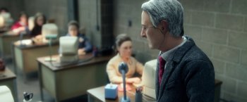 Movie still from “Anomalisa” (2015), directed by Duke Johnson – A man in a suit sitting at a table with a microphone; Close Up shot, Over the shoulder angle