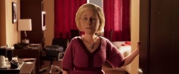 Movie still from “Anomalisa” (2015), directed by Duke Johnson – A woman in a pink sweater is standing in front of a red curtain; Close Up shot, High angle