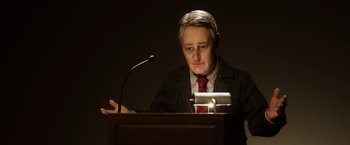 Movie still from “Anomalisa” (2015), directed by Duke Johnson – A man in a suit and tie sitting in front of a microphone; Close Up shot, Low angle