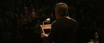 Movie still from “Anomalisa” (2015), directed by Duke Johnson – A man is speaking at a podium in front of an audience; Medium shot, High angle