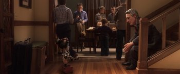 Movie still from “Anomalisa” (2015), directed by Duke Johnson – A group of people standing around a table with food on top of it; Wide shot, High angle