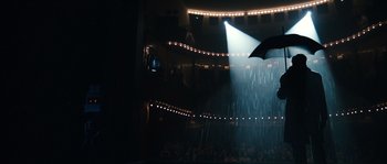 Movie still from “Anonymous” (2011), directed by Roland Emmerich – A crowd of people in a theater under a rain shower with an umbrella; Extreme Wide shot, Low angle