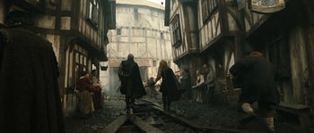 Movie still from “Anonymous” (2011), directed by Roland Emmerich – Two people are walking down a street in a medieval town; Wide shot, High angle