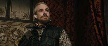 Movie still from “Anonymous” (2011), directed by Roland Emmerich – A man with a beard wearing a black vest; Close Up shot, Over the shoulder angle