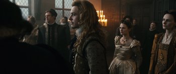 Movie still from “Anonymous” (2011), directed by Roland Emmerich – A group of people standing in a room with candles in the background; Medium shot, Over the shoulder angle