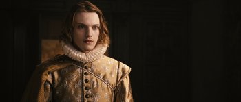 Movie still from “Anonymous” (2011), directed by Roland Emmerich – A man with long brown hair wearing a gold jacket; Close Up shot, Over the shoulder angle