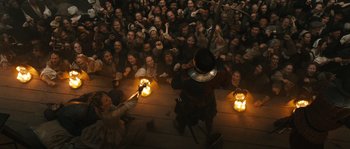 Movie still from “Anonymous” (2011), directed by Roland Emmerich – A group of people sitting around a stage with candles; Wide shot, High angle