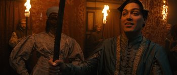 Movie still from “Anonymous” (2011), directed by Roland Emmerich – Two people in costumes holding a sword in front of a fire; Medium shot, Over the shoulder angle